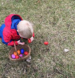 Child picking up plastic eggs in the grass at Rotary Park. 